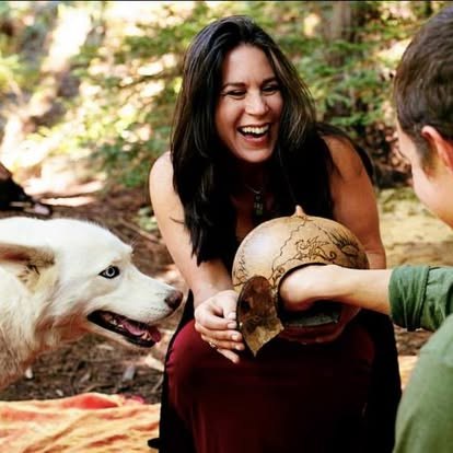 Leah laughing with a white wolf-dog in the forest