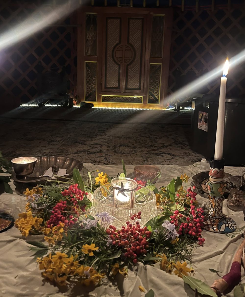A candlelit altar of flowers inside the yurt