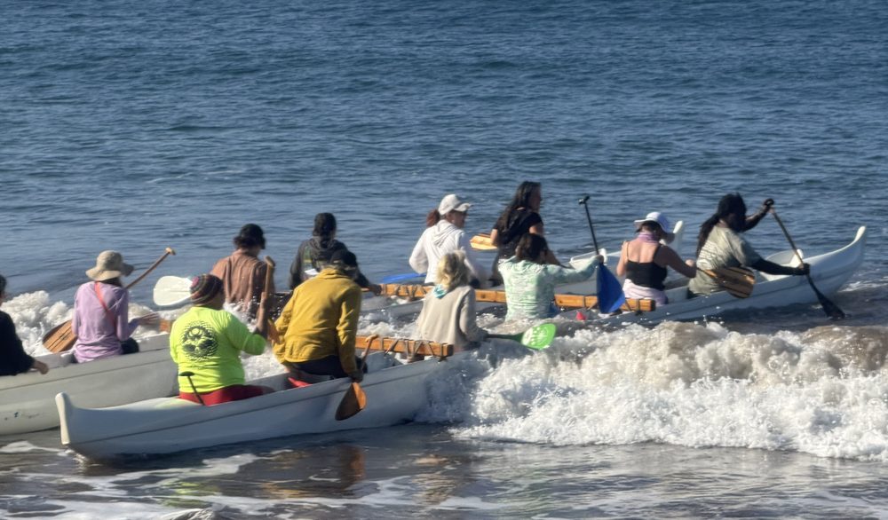 Paddling an outrigger canoe out through the waves