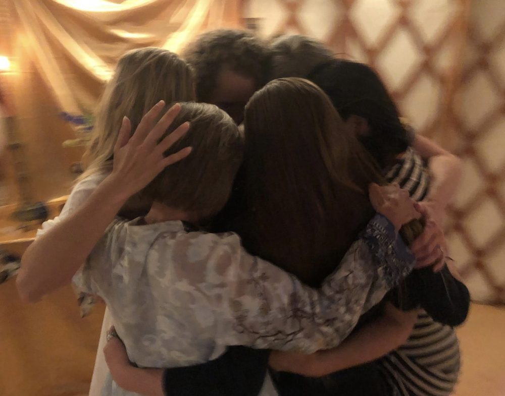 A group embrace inside the yurt