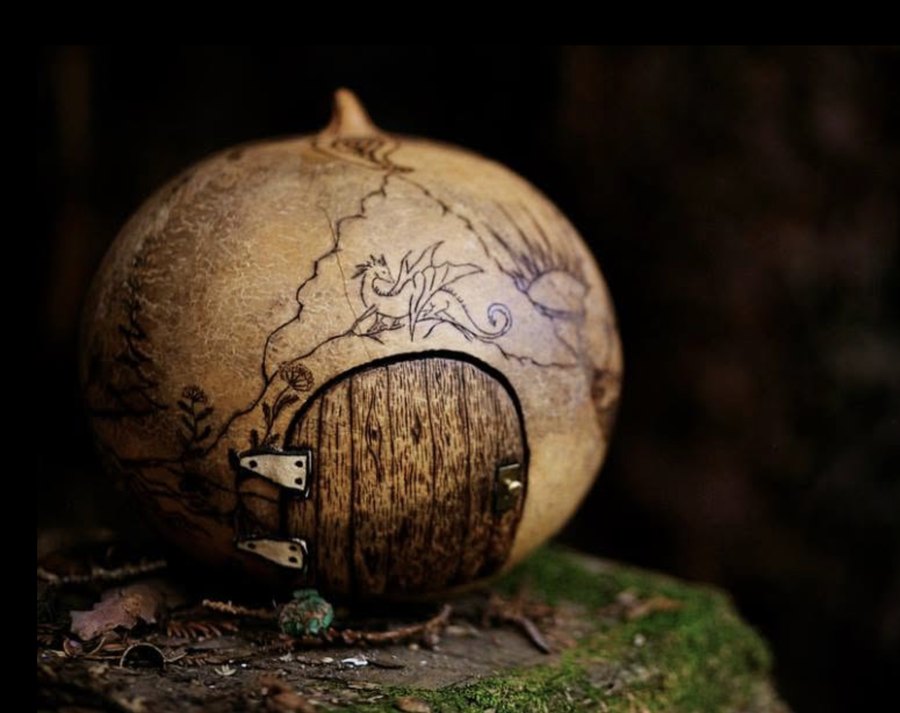 A tiny carved door with a dragon, on a moss-covered stump