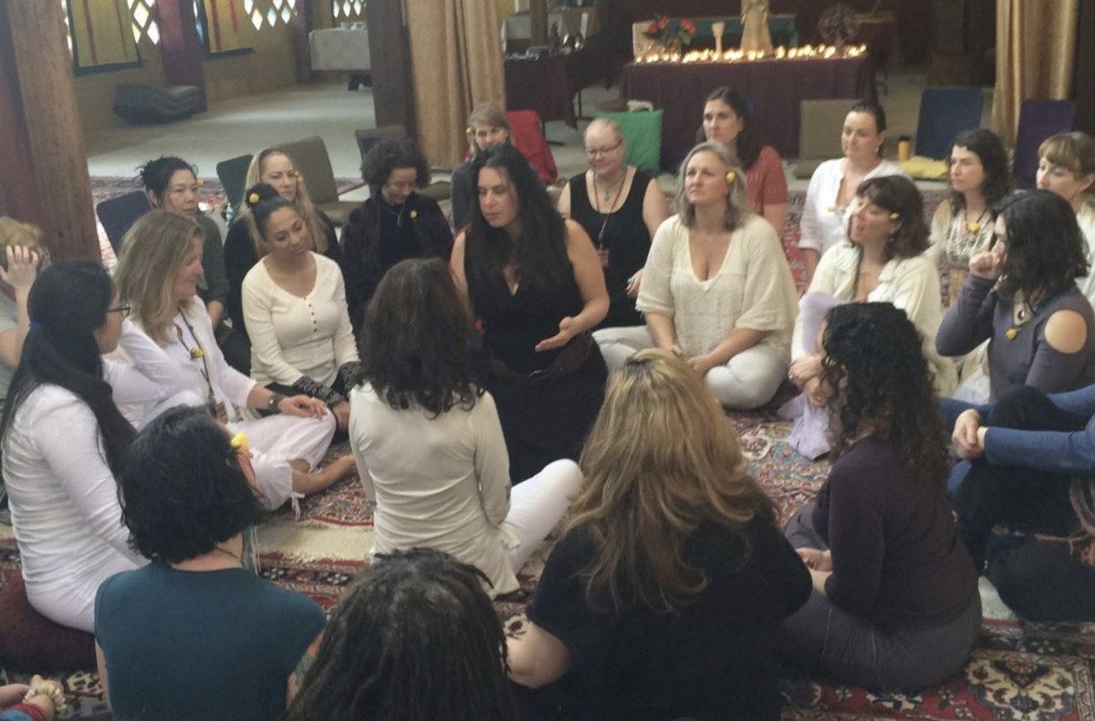 Leah in a women&rsquo;s story circle, seated together on rugs before an altar